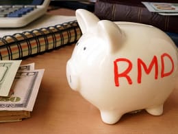 getty images piggy bank with rmd written on its side next to stack of paper money retirement savings k ira cash x bdf.jpg