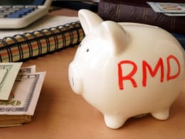 piggy bank with rmd written on its side next to stack of paper money retirement savings k ira cash.jpg