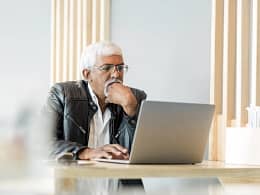 retired older man on laptop working reading news stocks.jpg
