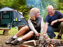 smiling couple roasting marshmallows at campsite.jpg