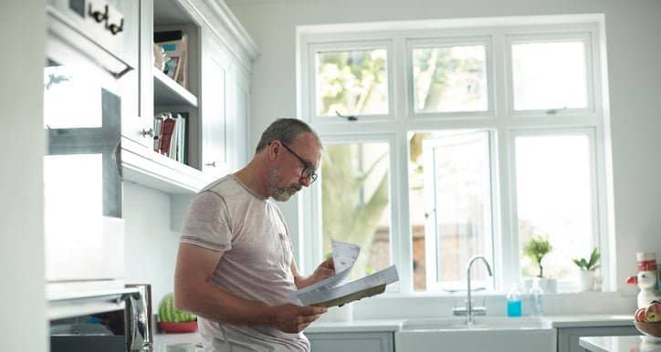 worried man in kitchen with bills fEoJV.width