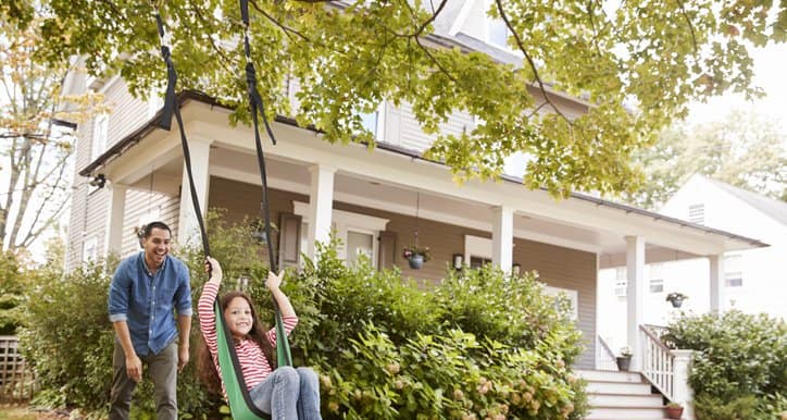 dad pushing daughter in swing in front yard.width .jpg