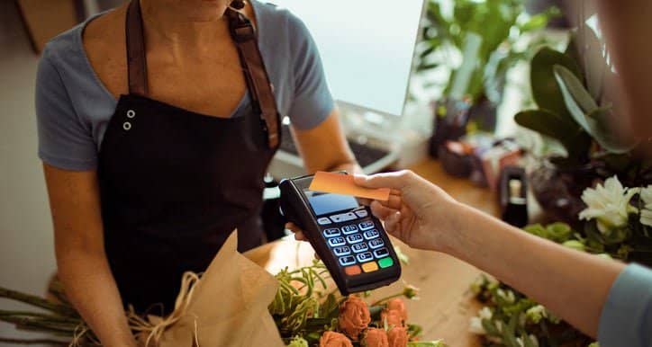 woman holding credit card over payment reader.width IAlpwc.jpg