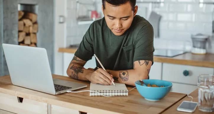 man at table writing in notebook NHASUaV.width .jpg