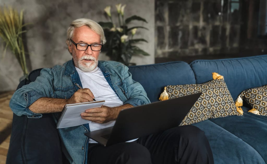 senior holding laptop and writing note in notebook.jpg