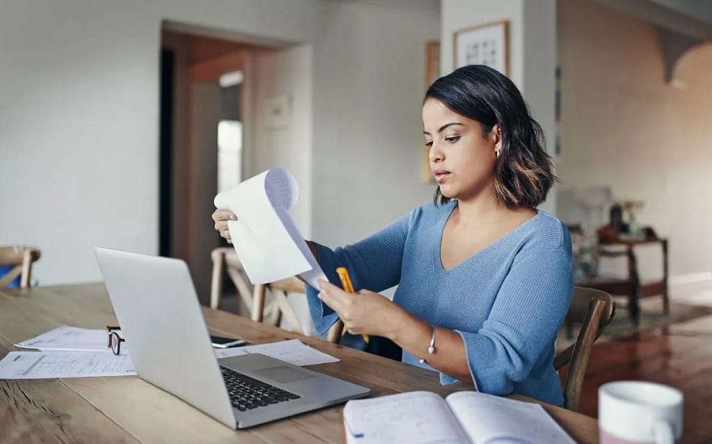 woman with bills and laptop in kitchen EEKd.width .jpg