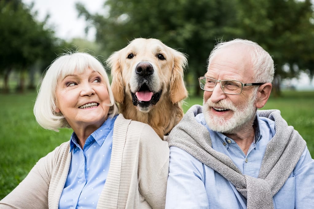 smiling senior couple looking at adorable dog