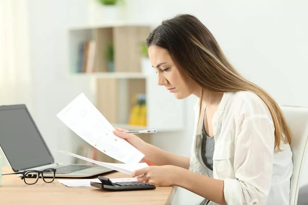 woman typing on calculator while looking at d.width qNdigi.jpg