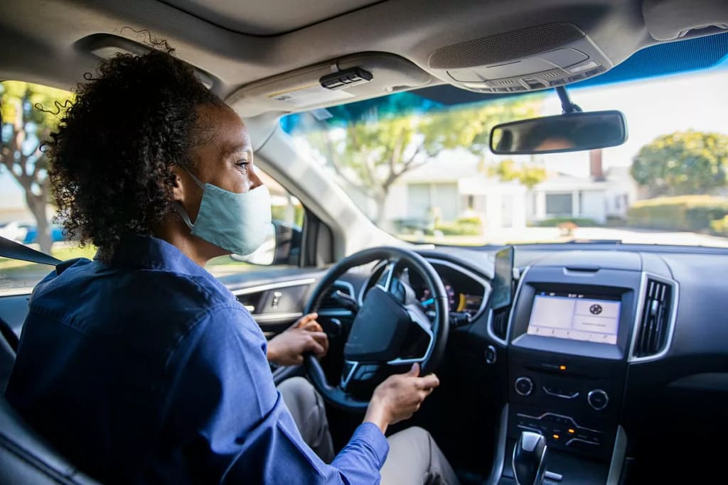 Woman wearing face mask driving her car and s.width HlXYHag.jpg