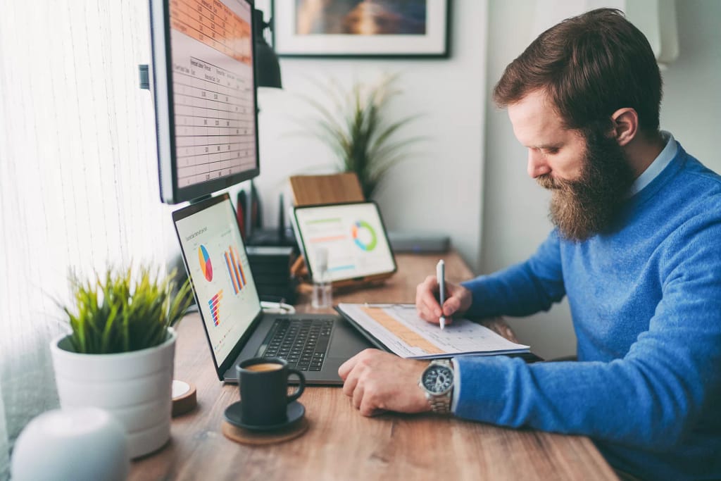bearded person at desk by computer taking notes.jpg