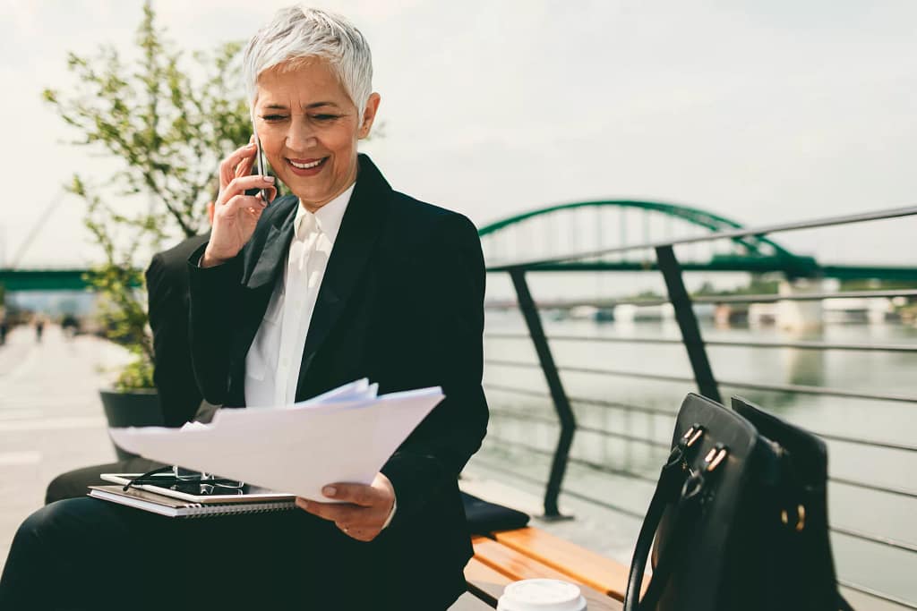 mature senior businesswoman woman on phone looking at documents.jpg