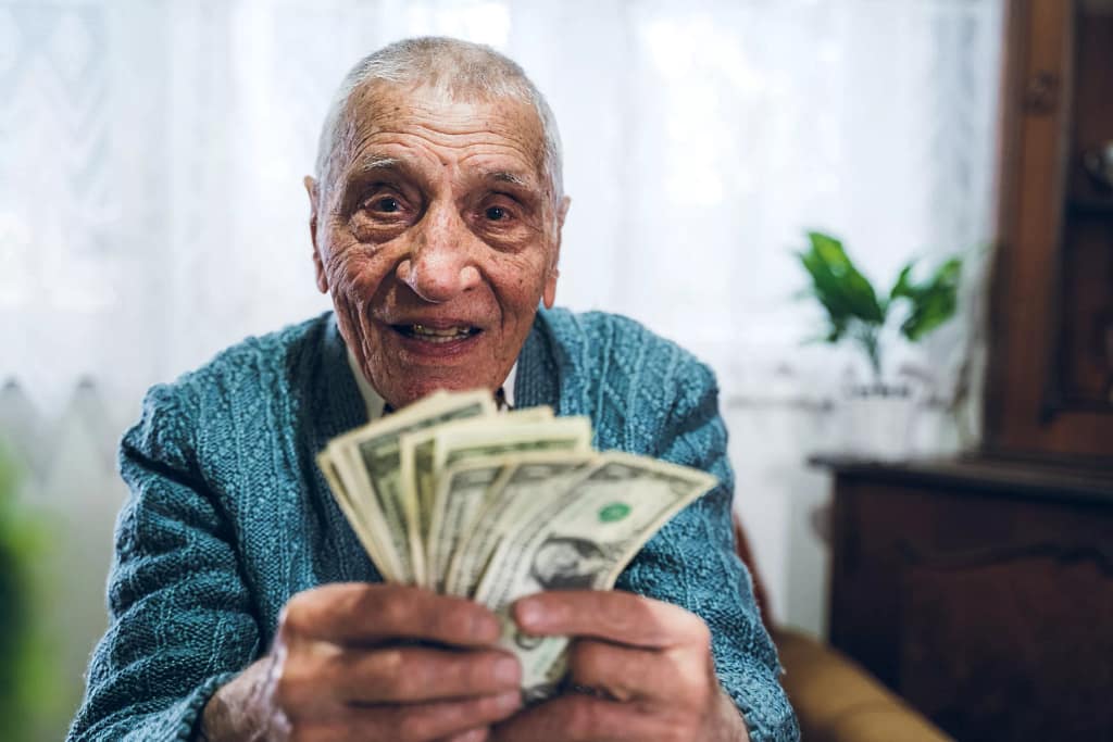 senior man counting cash money bills social security retire invest inflation cola getty.jpg