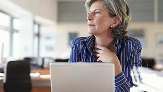 mature woman on laptop thinking and looking out window A52j1i