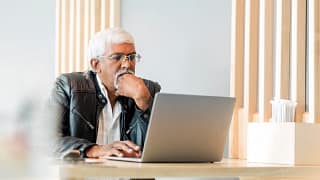 retired older man on laptop working reading news stocks eksKJU