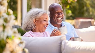 an elderly couple laughing drinking coffee kQKNDE