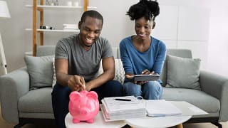 couple putting money in a piggy bank gettyimages JHHjH