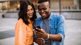 happy couple outdoors staring at phone
