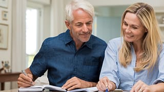 mature couple discussing finances with pens and paper
