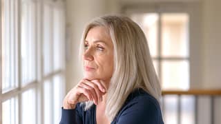 older person with serious expression looking out a window KZdjA