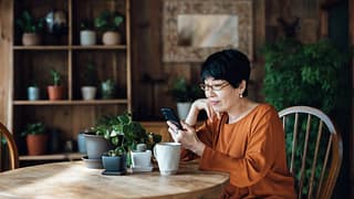 person sitting at a table using a smartphone emKMVr