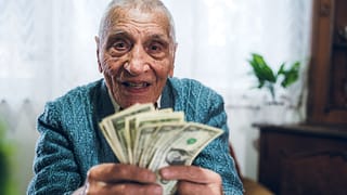 senior man counting cash money bills social security retire invest inflation cola getty LMwDR