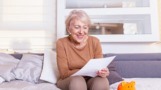 senior woman smiling reading document gettyimages