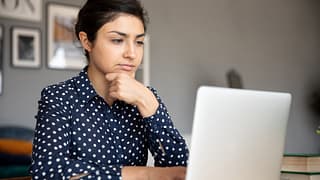 serious person with hand on chin looking at laptop