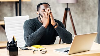 a person at a laptop covering their face gettyimages