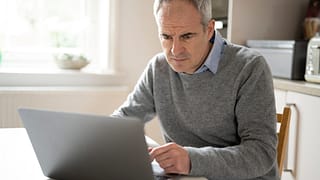 a person with a serious expression at a laptop gettyimages