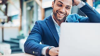 excited businessman with hand on head looking at laptop