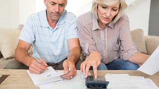 mature couple looking at documents and using calculator bills finances