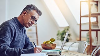 older man at laptop taking notes gettyimages