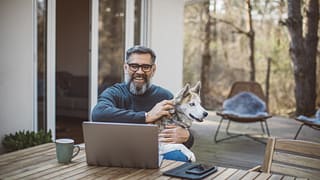 older man at laptop with dog gettyimages