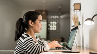person sitting at desk and typing on laptop