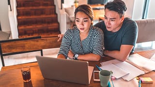 serious couple looking at laptop and discussing finances
