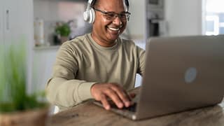 smiling person at laptop wearing headphones gettyimages