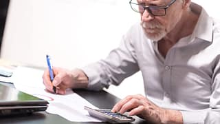 senior taking notes while using calculator gettyimages