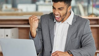 smiling person at laptop making celebratory fist gettyimages