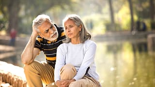 two older people sitting outside looking serious