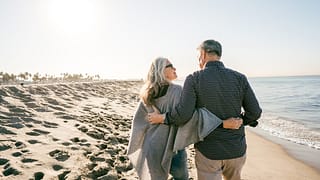 two people walking on the beach hugging