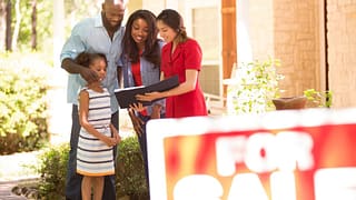 Couple and child in front of home for sale Tp.width