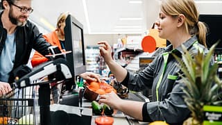 Grocery store employee ringing up customers .width