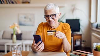 Mature woman smiling while holding credit car.width wrRdZh.jpg