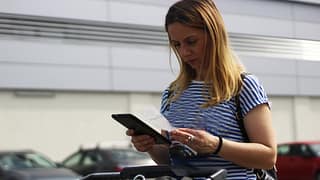 Woman in grocery store parking lot examining .width TGwgWbC