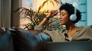 Woman listening to music through headphones. .width