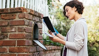 Woman sorting through mail at her mailbox mbL.width