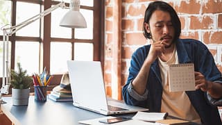 Young man pausing from using his laptop to lo.width GUCxw