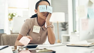 businesswoman covered in sticky notes while working on her taxes in an office