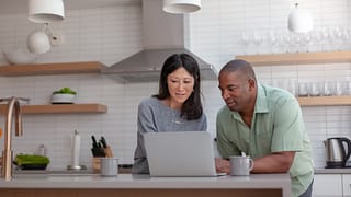 couple staring at computer in kitchen