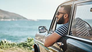 man in car at ocean.width